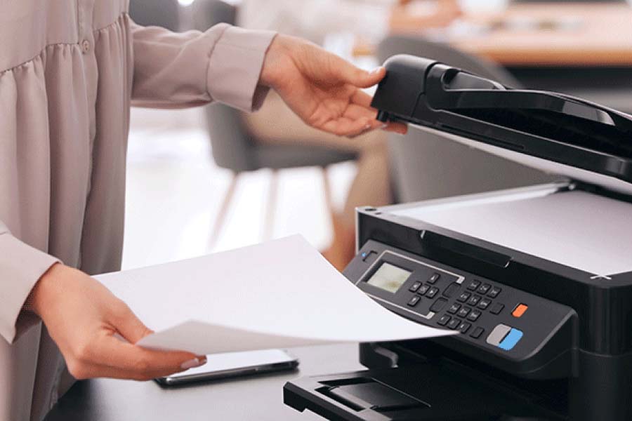 Woman using a printer and holding paper